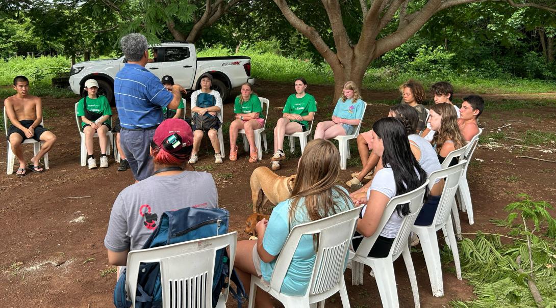 Group of conservation volunteers in Mexico sitting outside as they listen to placement supervisor's instructions